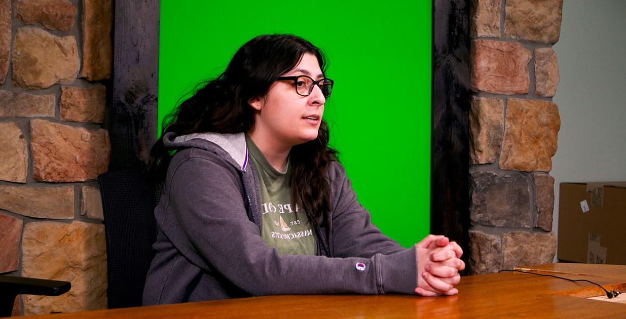 Zvi Gutierrez sitting at a desk with a green screen behind her